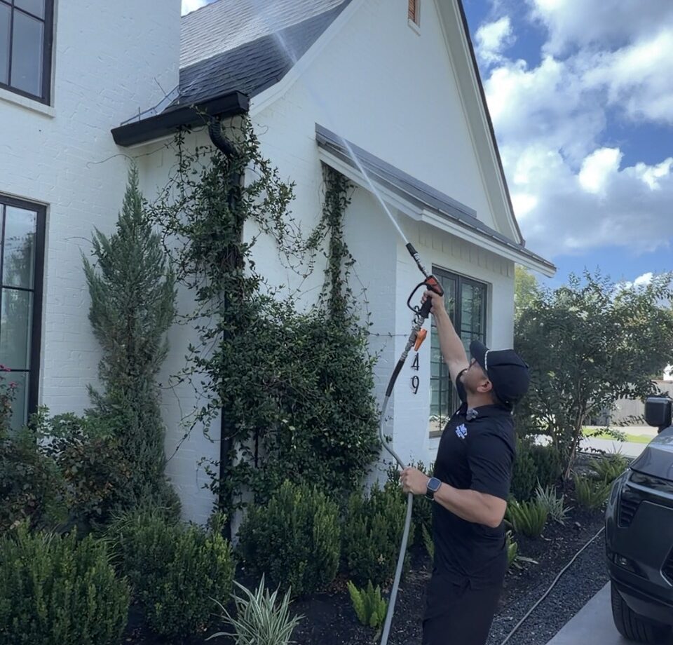 Roman, owner of 3G Pressure Pro, cleaning a house with the soft wash method in College Station TX