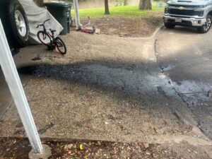 Heavy oil stain on a concrete driveway in College Station before pressure washing
