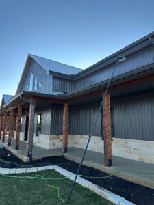 Soft washing the siding of a metal and stone home in College Station Texas