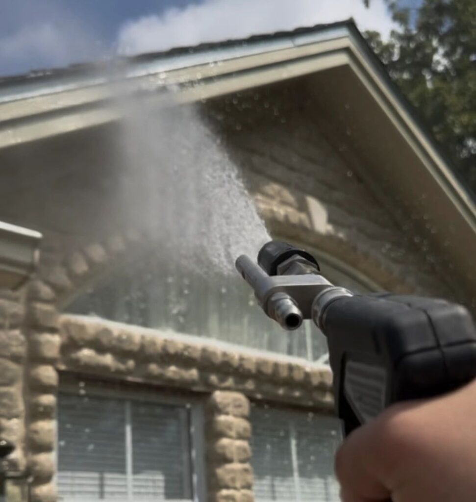 Soft washing a stone house exterior in Bryan Texas